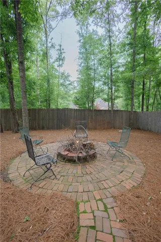 An inviting brick patio with a fire pit awaits outdoor gatherings, framed by a natural wood fence.