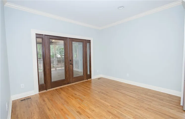 Rich hardwood flooring extends into a bright space, leading to double glass doors that open to an outdoor retreat.