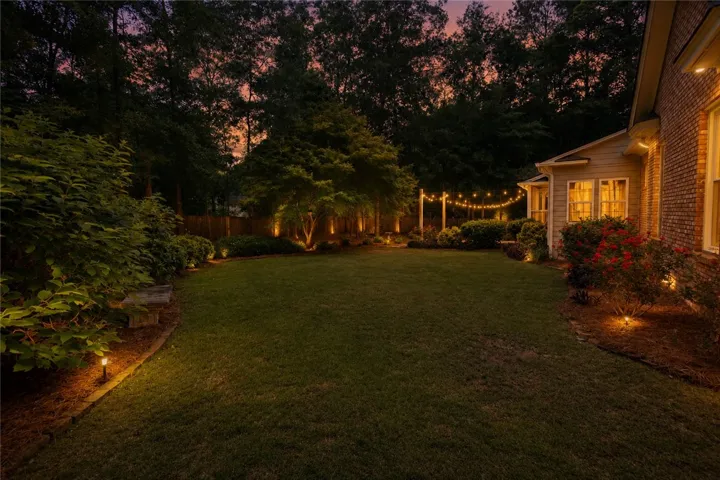 A well-maintained lawn and illuminated landscaping create an inviting outdoor living space.