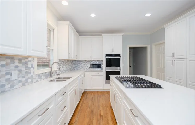 White cabinetry, stone counters, and hardwood floors combine for an elegant kitchen.