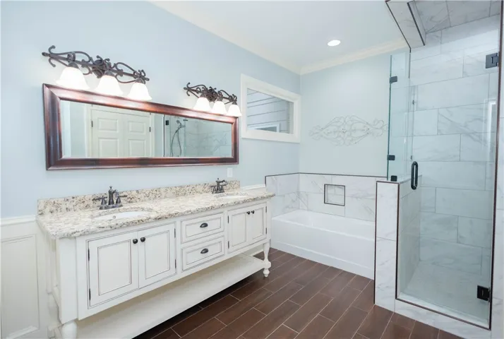 Dual vanity with a stone countertop and an elegant glass-enclosed shower create a serene bathing space.