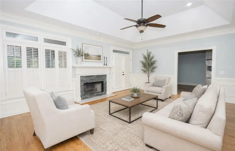 A refined living space showcases a stone fireplace, plantation shutters, and lustrous hardwood floors.