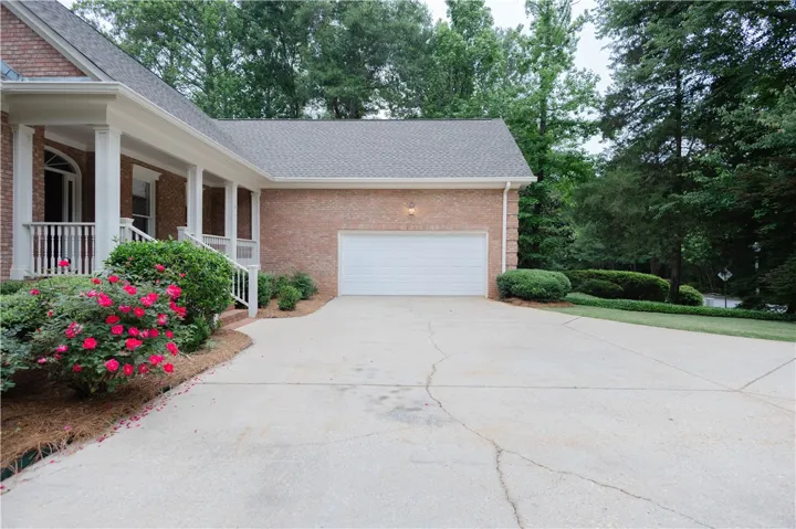 A well-maintained brick exterior with a welcoming porch and expansive driveway.