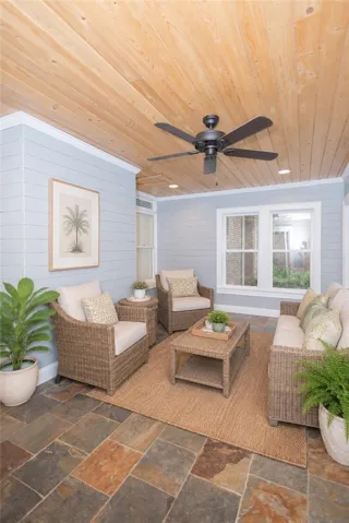 A relaxed sunroom retreat with natural wood ceilings and slate tile flooring offers comfortable indoor-outdoor living.