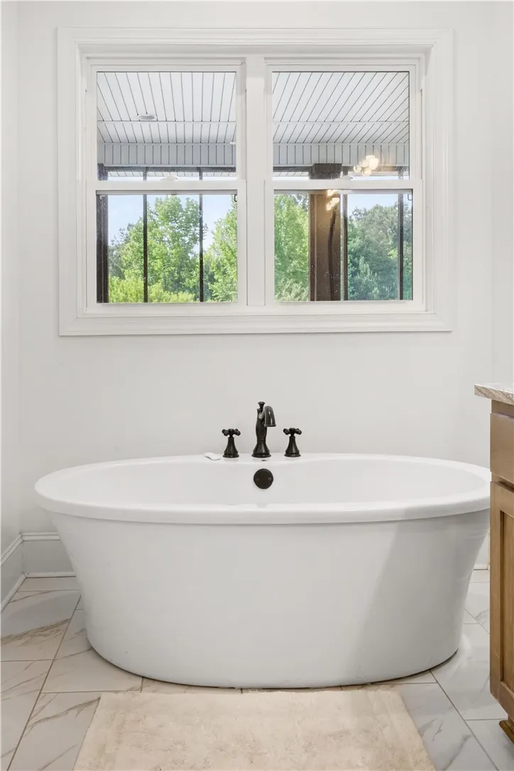 Indulge in relaxation with this elegant freestanding tub, perfectly placed under a naturally illuminated window.