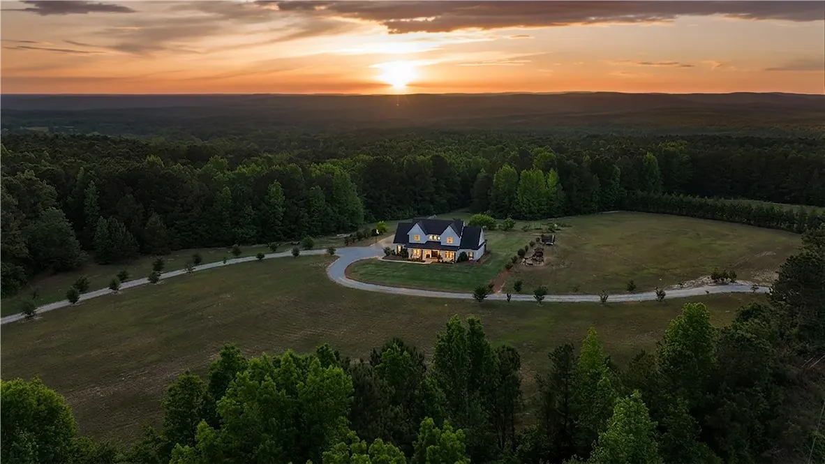 Perched on a sprawling, tree-lined property, this grand residence captures a vibrant sunset.