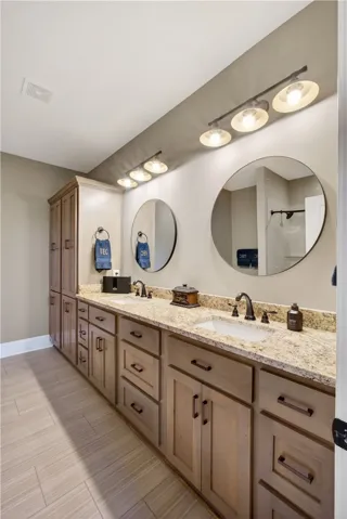 Double vanities with stone counters and modern circular mirrors elevate this well-appointed bathroom.