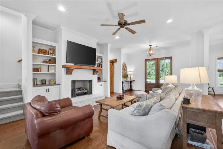A comforting living room offers a white brick fireplace with a mantle, complemented by rich hardwood flooring.