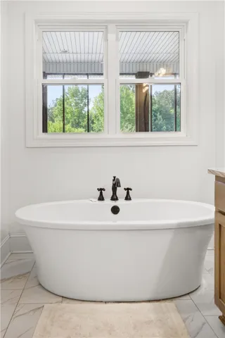 Indulge in relaxation with this elegant freestanding tub, perfectly placed under a naturally illuminated window.