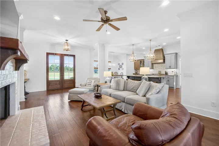 Hardwood floors and a white brick fireplace frame this inviting living space, leading to an open-concept kitchen.