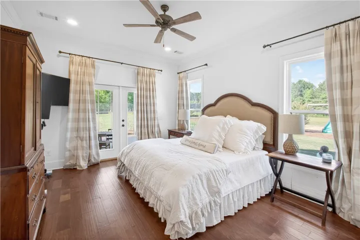 Hardwood floors and bright windows create a cheerful ambiance in this comfortable bedroom.