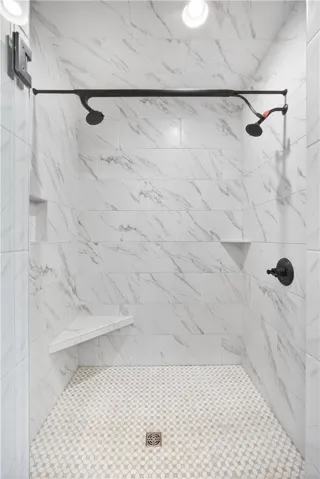 Marble-look tile and mosaic flooring create a refreshing walk-in shower experience.