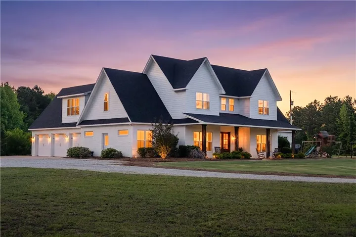 A spacious home with multiple gables and a welcoming porch glows under a beautiful twilight sky.