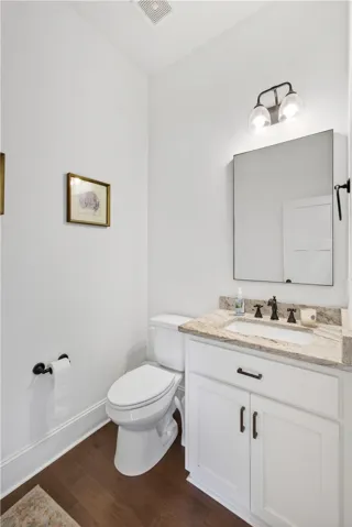 A well-appointed powder room features rich hardwood flooring and a vanity with a granite counter.