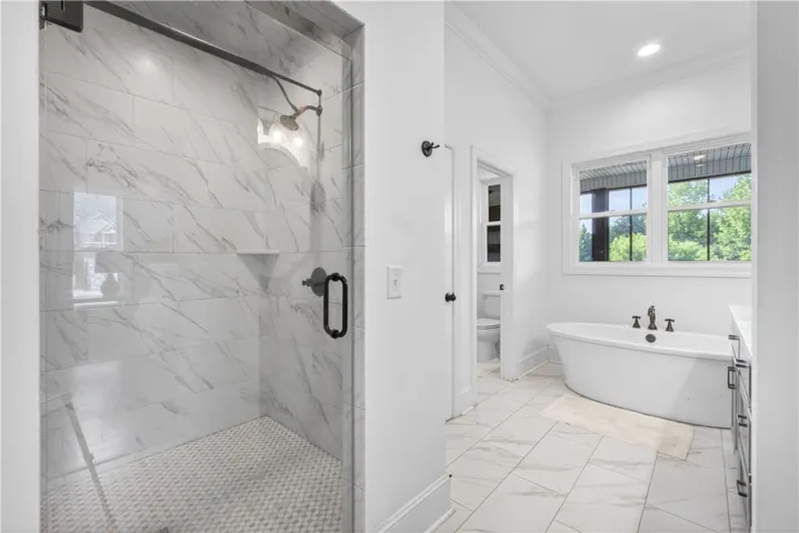 A spacious primary bathroom boasts a walk-in shower and a free-standing soaking tub.