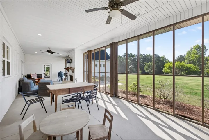 A spacious screened-in porch offers panoramic views of a lush green landscape.