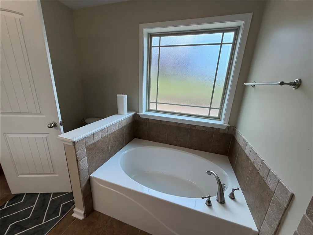 Corner soaking tub beneath an architectural window creates a private oasis.