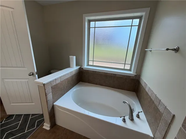 Corner soaking tub beneath an architectural window creates a private oasis.