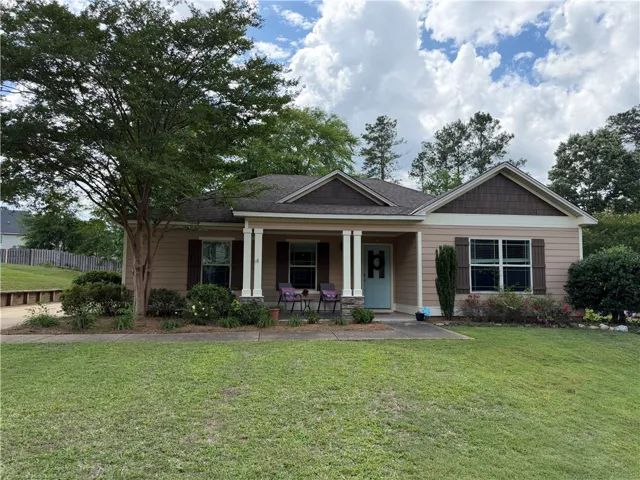 A charming single-story residence boasts a welcoming covered porch and meticulously maintained landscaping.