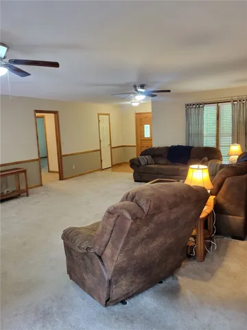 Comfortable living space featuring soft carpeting and multiple ceiling fans for optimal air circulation.