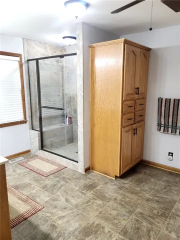 A well-appointed bathroom features a spacious walk-in shower with tile surround and a tall linen cabinet for storage.