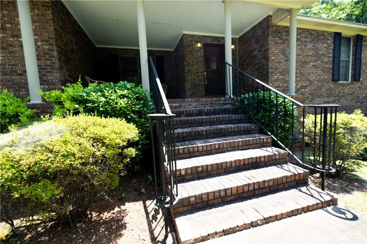A classic brick exterior with a welcoming entryway and mature landscaping creates appealing curb appeal.