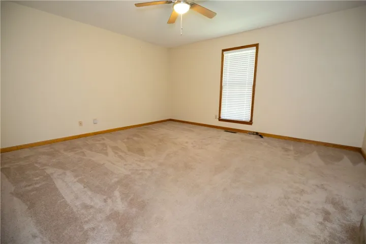A spacious bedroom featuring soft carpet flooring and a comforting ceiling fan for optimal airflow.