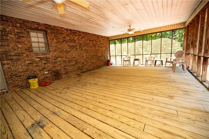 An inviting screened porch provides a perfect spot for relaxation, overlooking natural greenery.