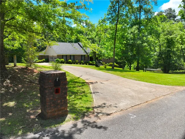 A long, winding driveway leads to this charming brick home nestled among mature, verdant trees.