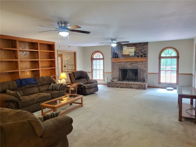 A spacious living area featuring a prominent brick fireplace and generous built-in shelving.