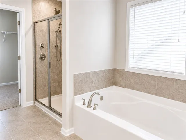 The primary bath includes a spacious step-in shower finished with full-height tile, as well as a soaking tub.