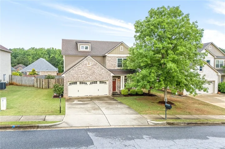 A classic brick and siding two-story home, with a spacious driveway leading to an attached two-car garage.