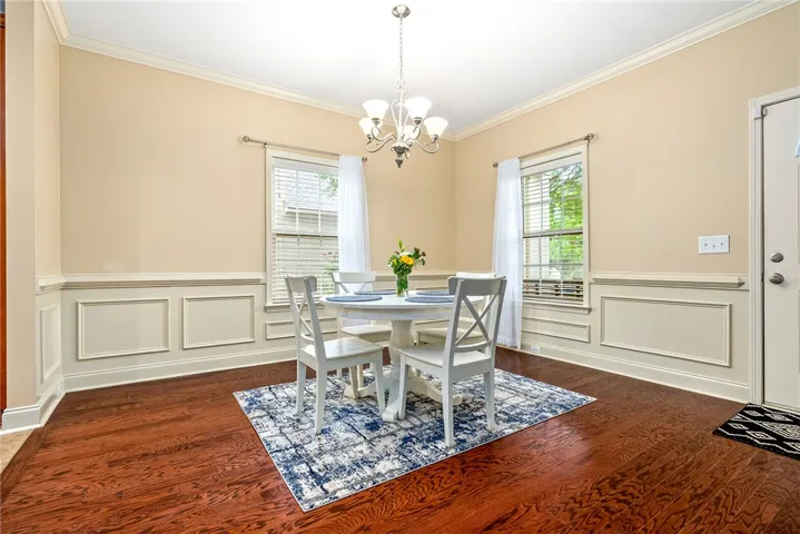 Elegant crown molding and wainscoting frame this inviting dining area with rich hardwood flooring.