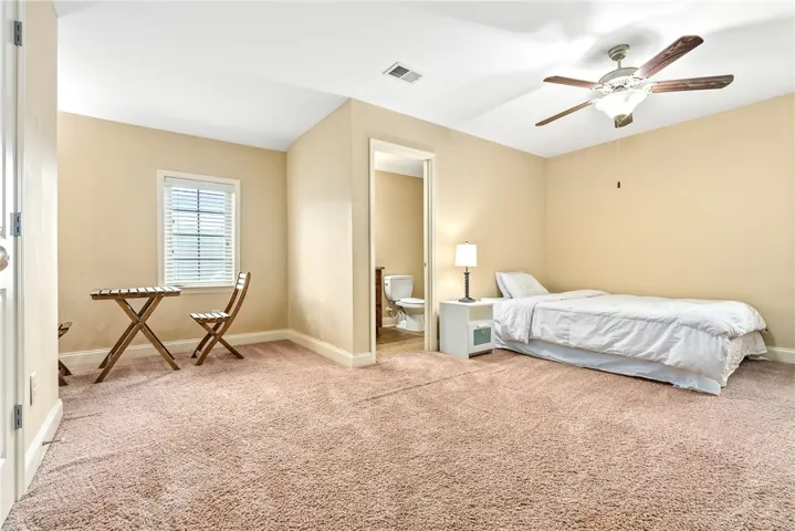 A quiet bedroom with plush carpeting, offering a private bath entry and ample natural light from a well-placed window.