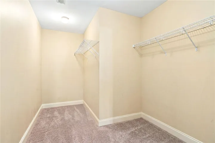 Functional closet with ample storage features wire shelving and plush carpeting.