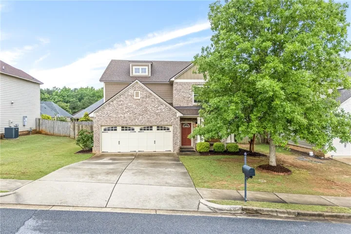 A classic brick and siding two-story home with an attached garage and mature landscaping.