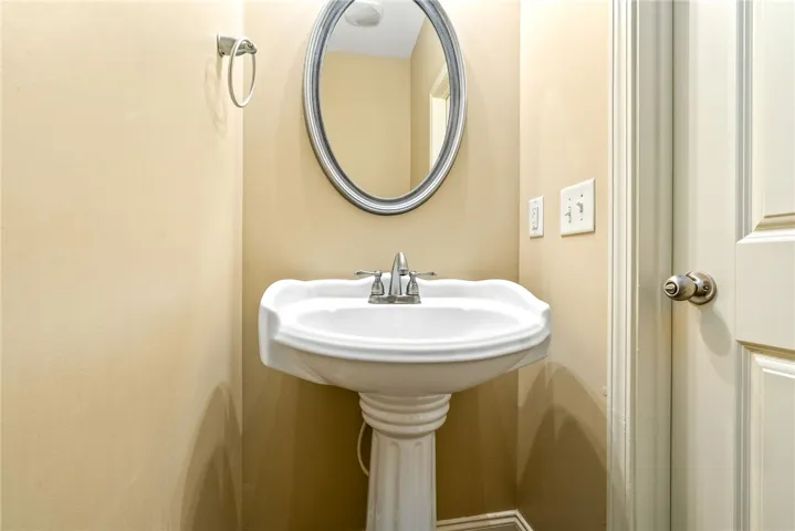 A pristine pedestal sink with a sleek oval mirror offers everyday convenience.