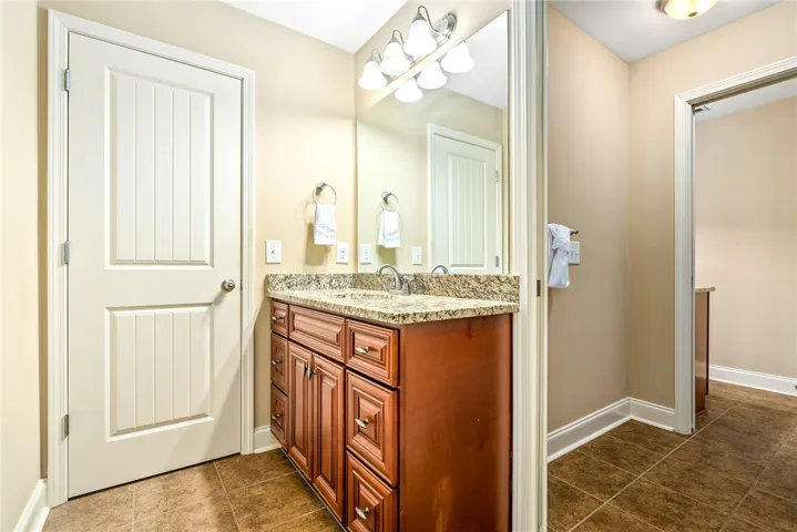 A well-appointed vanity with granite counters and rich wood cabinetry enhances this clean bathroom.