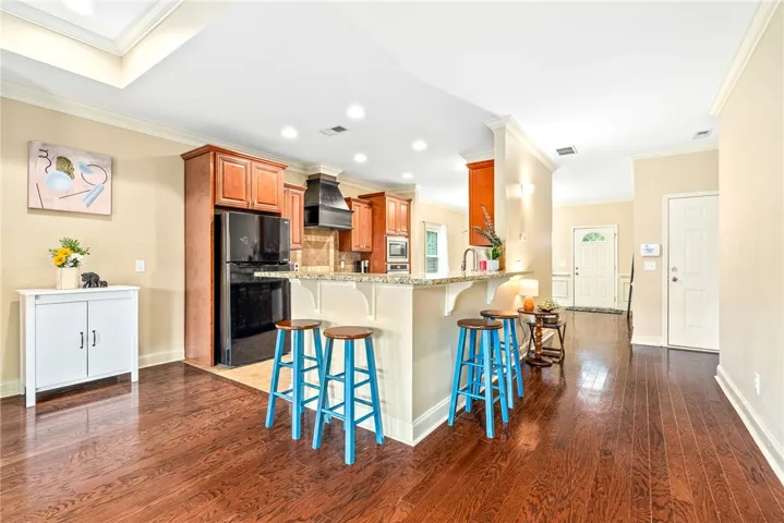 A well-appointed kitchen features a breakfast bar, gleaming hardwood floors, and abundant natural light.