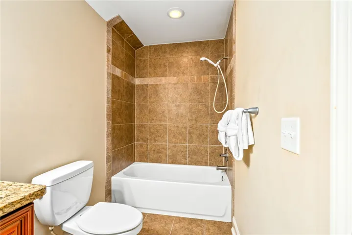 A convenient full bathroom presents a bathtub with shower and a vanity with granite counters.