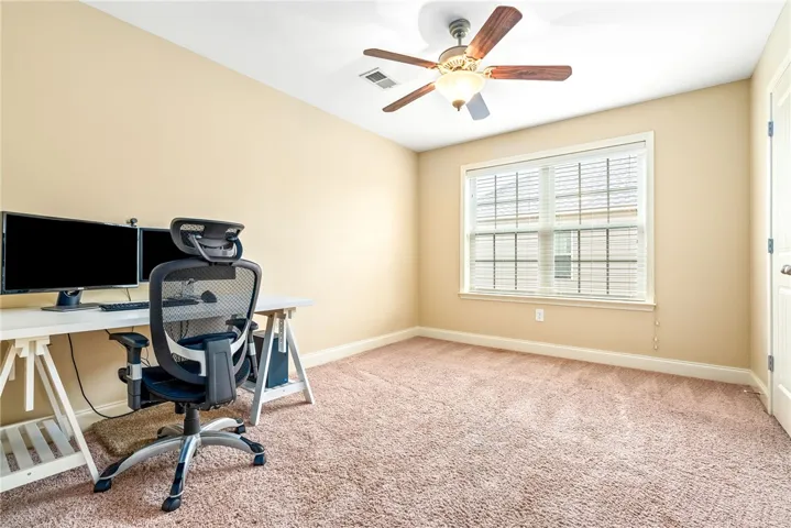 Functional office space featuring warm wall tones and a cozy carpeted floor, ideal for productivity.