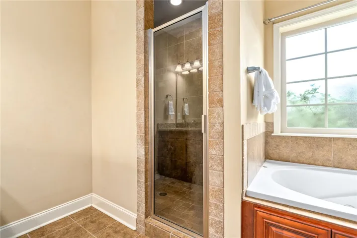 A corner soaking tub and glass-enclosed shower create a tranquil bathing retreat.