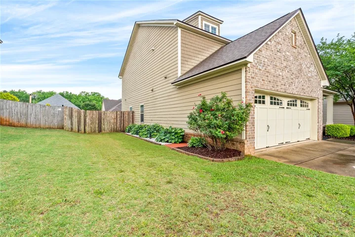 A well-maintained yard and side garden complement the inviting brick and siding exterior with a garage.
