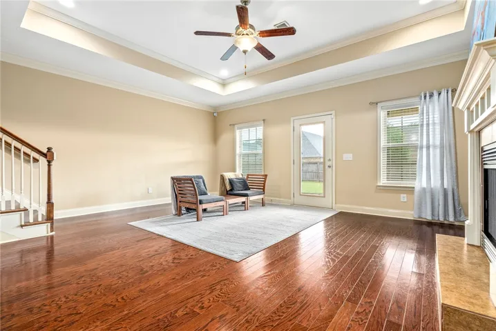 Refined wood floors and a tray ceiling frame this inviting living space, perfect for quiet moments or lively gatherings.