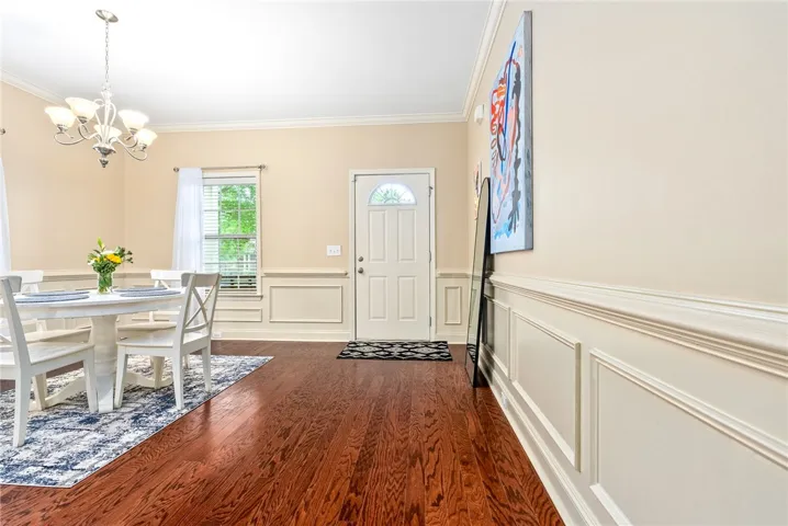 Rich hardwood flooring leads to an elegant entry with detailed wainscoting.