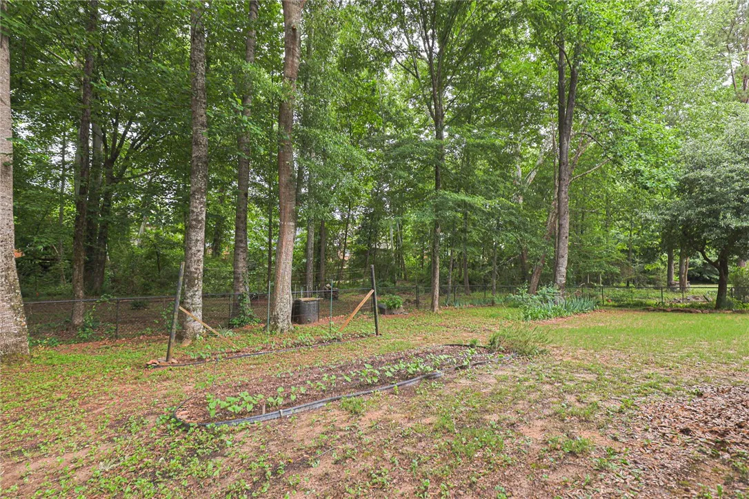 A verdant backyard offers a fenced garden and mature trees.