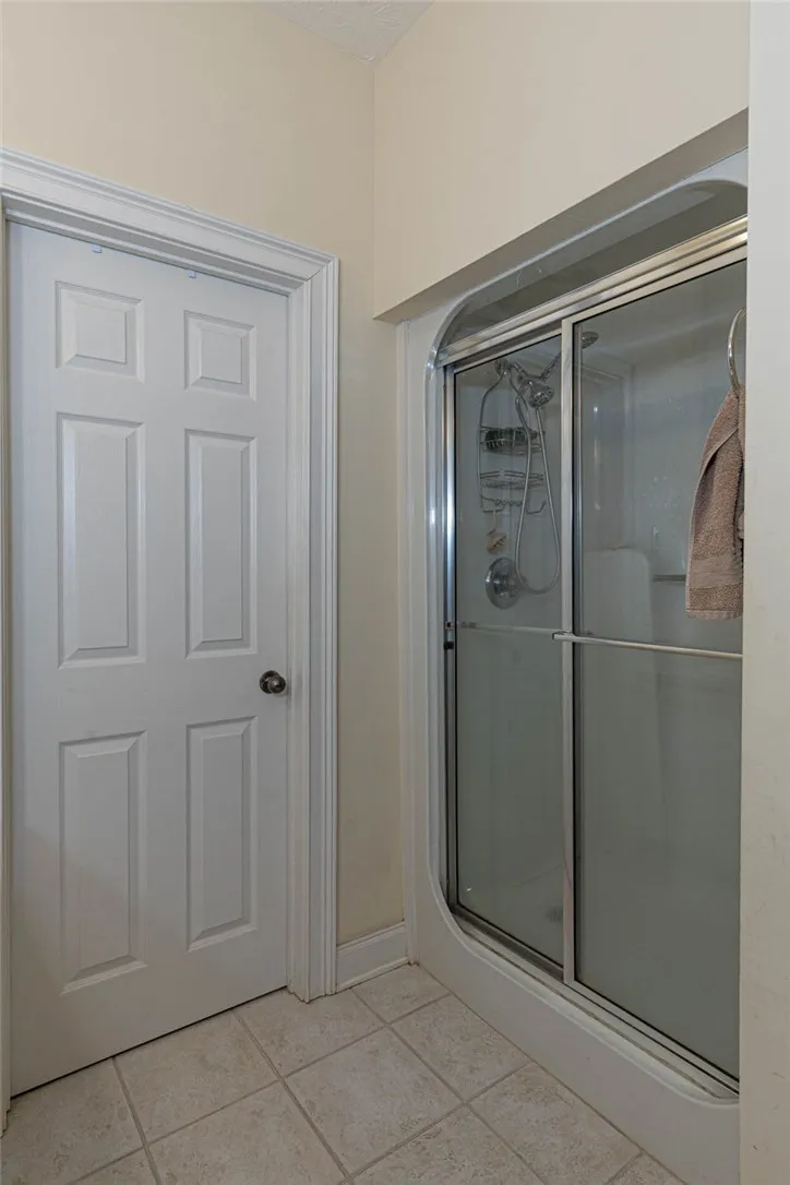 Step into a refreshing bathroom with a classic white six-panel door and a sleek, modern glass-enclosed shower.