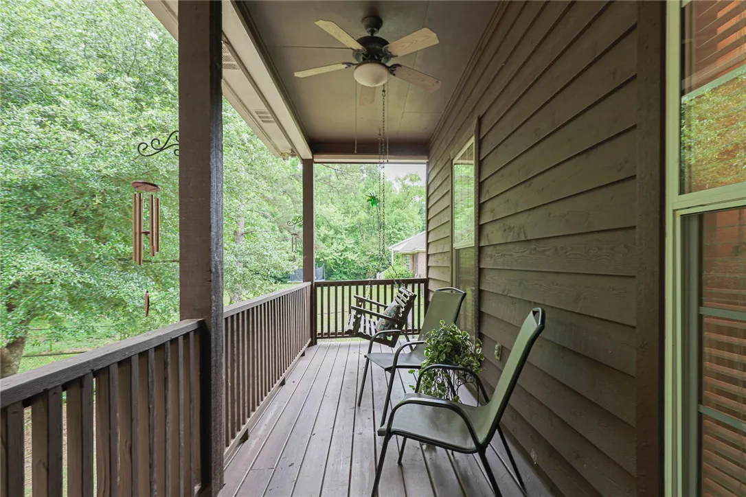 A spacious covered porch invites relaxation with a wooden deck and ceiling fan.