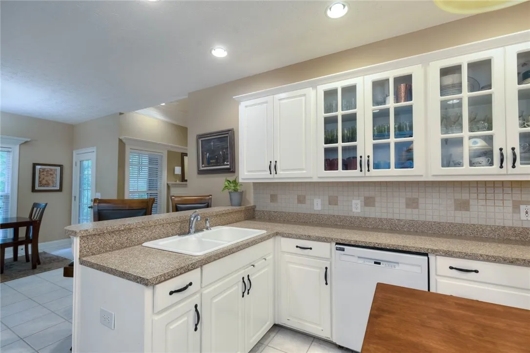 A well-appointed kitchen features ample counter space, a double sink, and sleek white cabinetry.