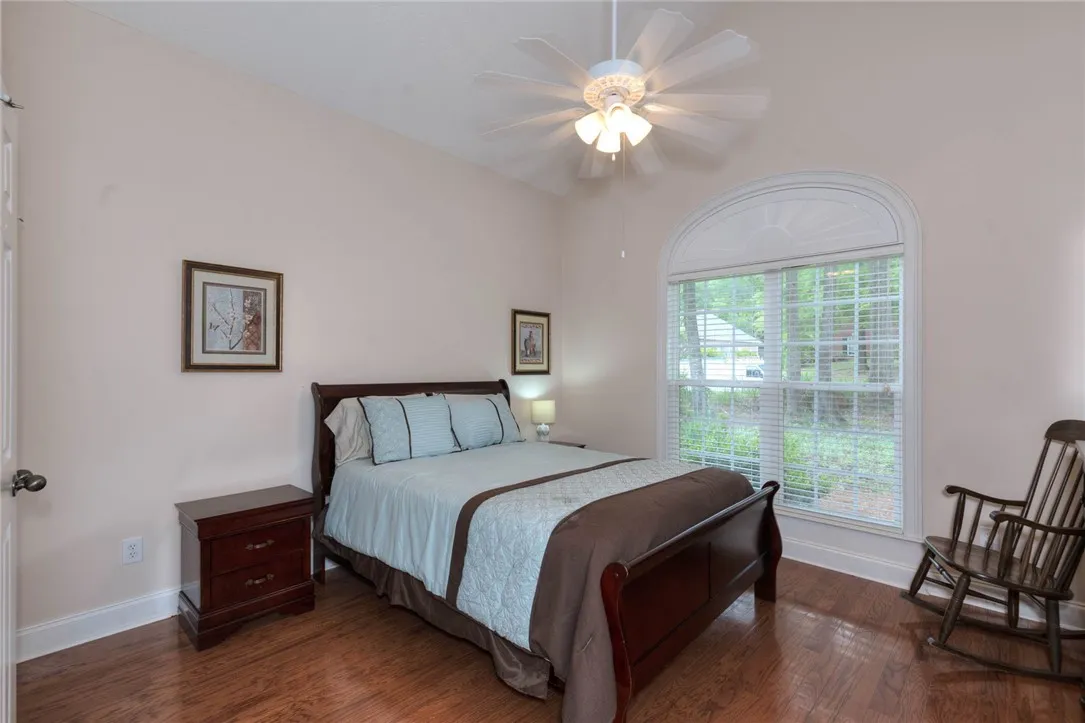 Hardwood floors and a grand arched window grace this comfortable bedroom.